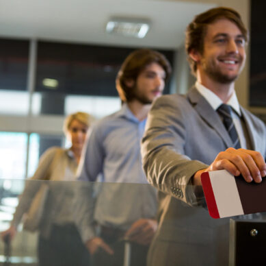Businessman standing with boarding pass at check-in counter in airport